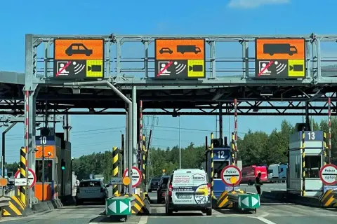 Bramki A4 z wyświetlaczami informującymi o typie pojazdu i opłatach. Samochody i ciężarówki zbliżają się do punktów poboru opłat.