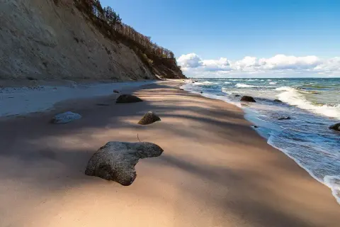 Plaża z klifem i kamieniami, fale Bałtyku. Wyobraź sobie, że to jedne z **polskich wysp na Bałtyku**, gdzie natura tworzy dzikie krajobrazy.