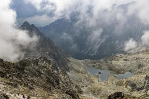 Widok na Tatry z mgłą, idealne miejsce na pierwsze górskie wędrówki. Szlak prowadzi w dół do malowniczych jezior.