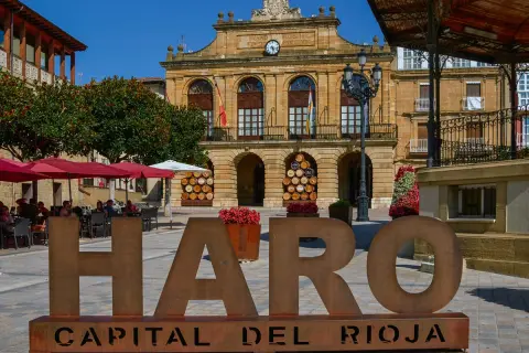 Letras gigantes "HARO CAPITAL DEL RIOJA" en plaza con Ayuntamiento y terraza. Descubre qué ver en Haro.