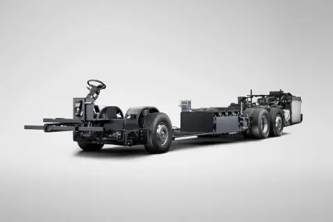 Châssis d'un bus Scania hybride, prêt à être assemblé, avec son volant et ses roues visibles.