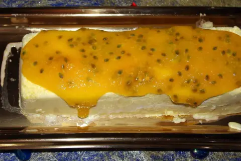 Gâteau glacé rectangulaire nappé d'un confit mangue passion aux graines visibles, sur un plateau doré.