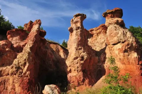 Les formations rocheuses ocreuses de la vallée des Saints en Auvergne, sculptées par le temps, se dressent sous un ciel bleu éclatant.