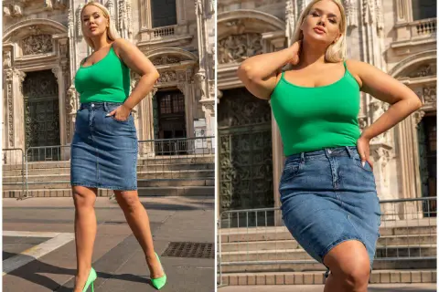 Kobieta w zielonym topie i jeansowej spódnicy plus size, pozuje na tle zabytkowej budowli.