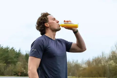 Sportler trinkt nach dem Training ein Getränk. Wann Elektrolyte nehmen? Nach dem Sport ist die beste Zeit.