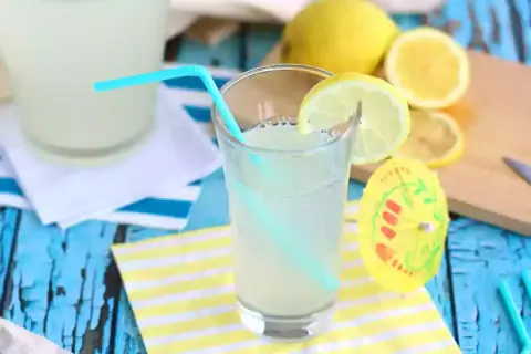 Ett glas hemgjord lemonad med citronskiva och sugrör. Perfekt för ett enkelt lemonad recept en varm sommardag.