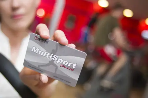 Karta MultiSport Plus w ręce na tle siłowni.