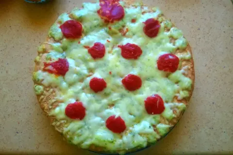 Domowa pizza z serem, zielonym sosem i czerwonymi kółkami pepperoni.