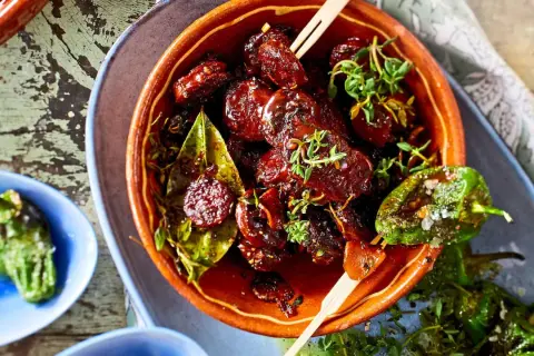 Leckeres Tapas Fingerfood: Glasierte Datteln mit Kräutern und geröstete Pimientos de Padrón.