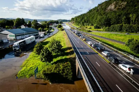 Trafikkaos vid en översvämmad rastplats. Bilar står stilla på motorvägen, en lastbil har fastnat i vattnet.