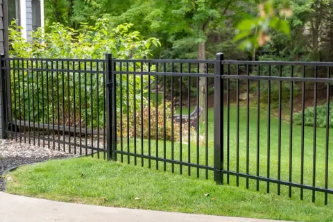 A newly completed metal fence installation encloses a lush green lawn and garden area, providing a sleek and secure boundary.