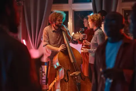Muzyk z kontrabasem i goście z winem. Stylizacja na koncert jazzowy: swobodna elegancja.