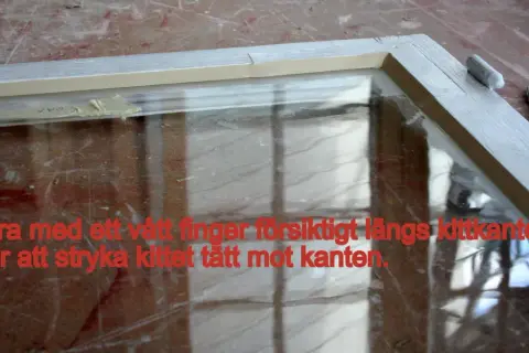 Fönsterkarm med nyligen applicerat kitt. Dra med ett vått finger längs kittkanten för att jämna till.