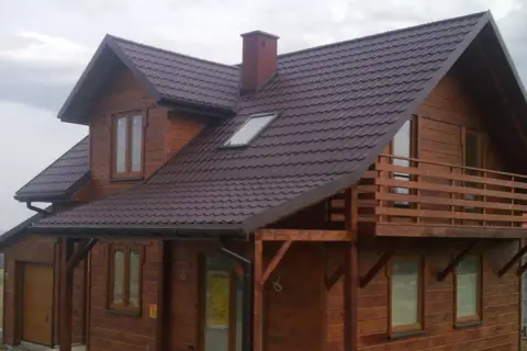 Drewniany dom pod klucz, gotowy do zamieszkania. Piękna, brązowa dachówka i przestronny balkon.