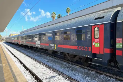 Ein langer Zug mit der Aufschrift "Intercity notte" und "DELUXE" steht am Bahnsteig. Vielleicht geht es **mit dem Zug nach Griechenland**?