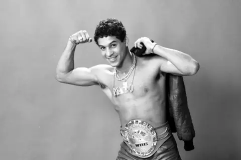 Boxaren Hector Camacho poserar stolt med sitt WBC-mästarbälte och en läderjacka över axeln.
