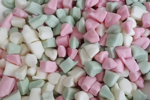 En hög med Ahlgrens bilar fluff i rosa, vitt och grönt. De ser mjuka och fluffiga ut, redo att ätas.