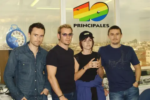 The Cranberries, marząc o sukcesie, pozują przed logo 40 Principales.