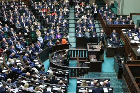 Posłowie w sali sejmowej, dyskutują o tym, ile wynosi dieta poselska.