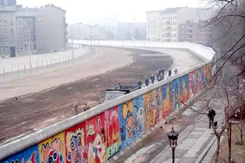 Kolorowy Mur Berliński, świadectwo czasów, kiedy wzniesiono mur berliński, z ludźmi spacerującymi po chodniku.