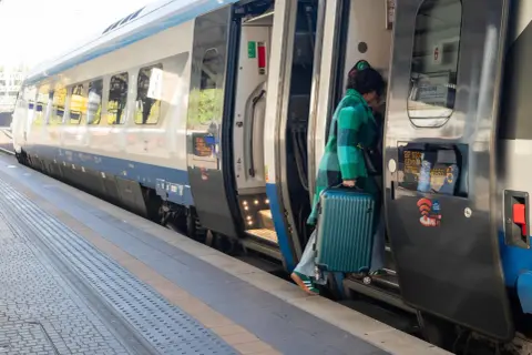 Kobieta z walizką wsiada do pociągu Pendolino. Szybkość i komfort podróży to jego znaki rozpoznawcze.
