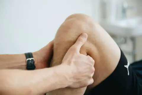 Un kinésithérapeute examine le creux poplité d'un patient, peut-être pour diagnostiquer une douleur ou une blessure.