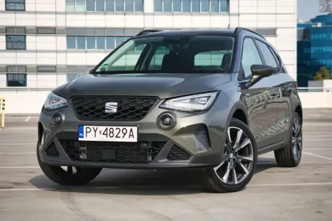 Szary Seat Arona 1.0 TSI zaparkowany przed nowoczesnym budynkiem.