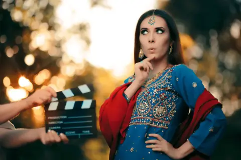 Kobieta w tradycyjnym indyjskim stroju i klaps filmowy na planie.
