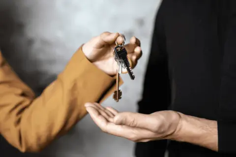 Mani che si scambiano chiavi, simbolo di un immobile in comproprietà abitato da un solo proprietario.