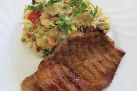 Ein saftiges Schweinefilet mit einem bunten spanischen Salat, garniert mit Petersilie.