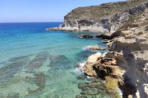Aguas cristalinas y rocas escarpadas en la playa del embarcadero. Un lugar idílico para disfrutar del sol y el mar.