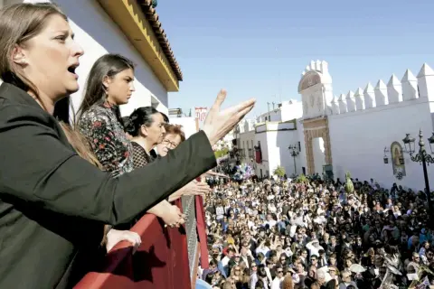 Mujeres en un balcón observan una multitud y escuchan saetas populares.