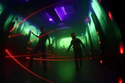 Dzieci bawią się w laserowym labiryncie w Krakowie, unikając czerwonych promieni.