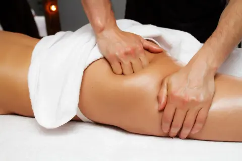 Mains expertes travaillant sur la fesse, soulageant la tension du massage piriforme. Douceur et détente assurées.