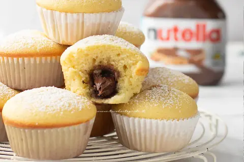 Muffin soffici con cuore di Nutella, perfetti per una ricetta muffin semplici e golosa. Spolverati di zucchero a velo.