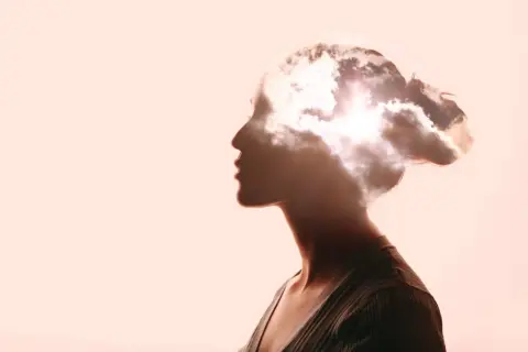Kopfprofil einer Frau, in dem sich Wolken und Sonne spiegeln. Ein Symbol für die Weite des Denkens, die für Berufe in der Philosophie und deren Gehalt relevant ist.