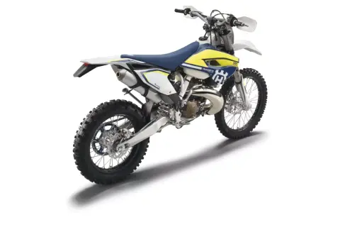 Husqvarna TE 250 gotowy do jazdy po bezdrożach. Biało-żółty motocykl terenowy z niebieskim siedzeniem.