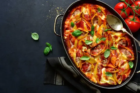 Conchiglioni farcis à la sauce tomate et au fromage, prêts à faire lever la pâte au four. Garnis de basilic frais.
