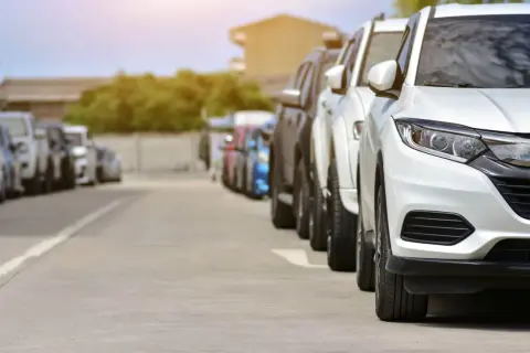 Rząd białych i ciemnych samochodów na parkingu. Może to być scena z transakcji, gdzie nastąpiło zaniżenie wartości samochodu na umowie.