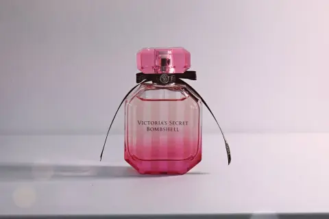 Różowa butelka kultowych perfum damskich Victoria's Secret Bombshell z czarną wstążką.