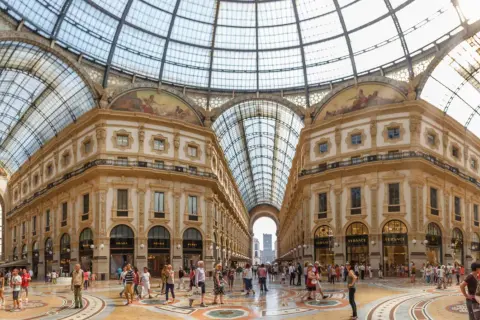 La Galleria Vittorio Emanuele II, un capolavoro architettonico con vetrate luminose e negozi di lusso, accoglie visitatori a Milano.