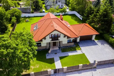 Piękny dom z czerwonym dachem i ogrodem. Zastanawiasz się, ile kosztuje projekt domu?