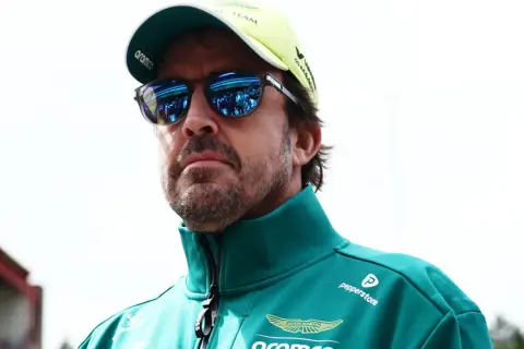 Alonso hoy, con gafas de sol reflejando el paddock, viste un polo verde de Aston Martin.