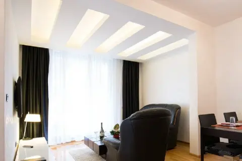 Nowoczesny salon z designerskim plafonem led, który subtelnie rozświetla wnętrze. Drewniane elementy dodają ciepła.
