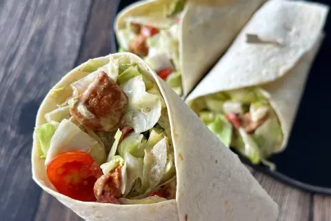 Pyszna tortilla z kurczakiem, chrupiącą sałatą, pomidorkami i kremowym sosem. Idealna na szybki lunch.