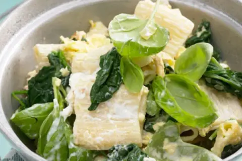 Herzhafte Spinat Ricotta Tortellini mit frischem Spinat und cremiger Sauce in einer Schüssel.