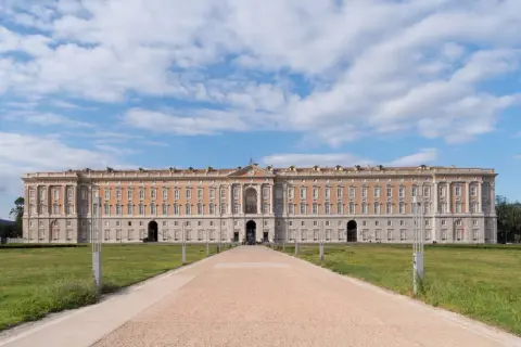 Reggia di Caserta, la piazza più grande d'Italia, con il suo imponente palazzo reale e un viale che conduce verso l'ingresso principale.