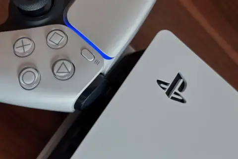 Zbliżenie na biały kontroler PlayStation 5 i konsolę z logo.