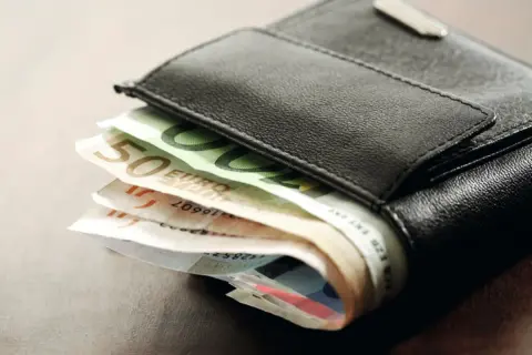 Schwarzes Lederportemonnaie mit Euro-Scheinen. Die Scheine deuten auf die Gehaltszahlung nach dem tarifvertrag wohnungswirtschaft eingruppierung hin.