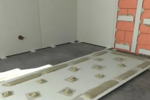 Płyta GK z masą klejącą gotowa do montażu. Pokazuje, czym przykleić płytę GK do ściany, stosując metodę "placków" i "wstęg".
